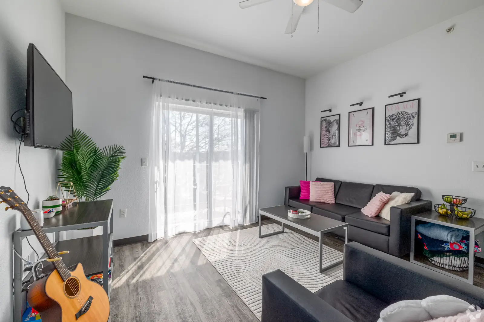 Living room at The Qube with sofa, chairs, coffee table, TV, and balcony access